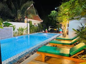 a swimming pool with green seats next to a house at Green Island Bungalows in Kampot
