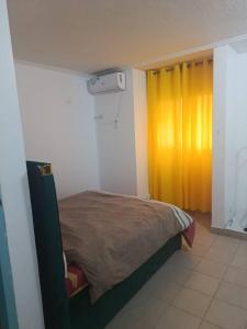 a bedroom with a bed and a yellow curtain at Chambre aménagée dans un hôtel in Douala
