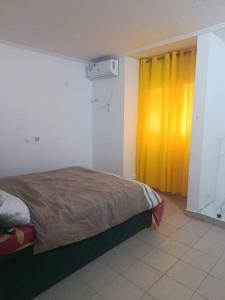 a bedroom with a bed and a yellow curtain at Chambre aménagée dans un hôtel in Douala +1 photo