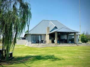 a house with a table and chairs in a yard at Vaal Dam Manor - Waters Edge in Oranjeville