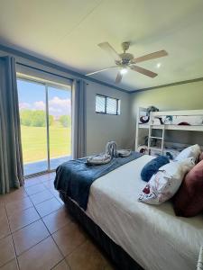 a bedroom with a bed with a ceiling fan and a window at Vaal Dam Manor - Waters Edge in Oranjeville