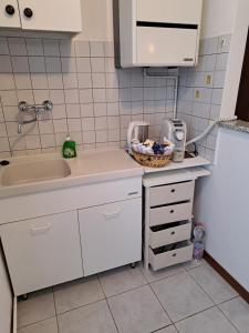 a kitchen with white cabinets and a sink and a basket at Green & Blue House in Valbrona