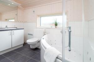 a bathroom with a tub and a toilet and a sink at Resort 2 Sea Lodge C 51 in Großenbrode +28 photos