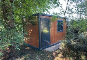 a wooden shed with a door in the woods at Les cabanes de Condé in Condé-sur-Vesgre +5 photos