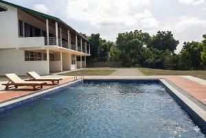 a swimming pool next to a building with a house at Bundala Forest Resort Yala in Weerawila