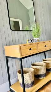 a vanity with a mirror and a table with baskets at Briar & Bloom2 in Hilton +4 photos