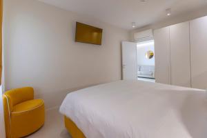 a bedroom with a white bed and a yellow chair at Opera Relais De Charme - Aparthotel in Verona