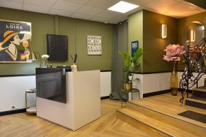 a waiting room with a tv and flowers at Logis Hôtel Maison Voltaire in Amboise