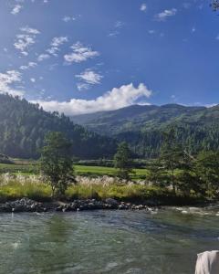 a river with rocks and trees and mountains in the background at Lanying Riverview Homestay in Dirang Dzong