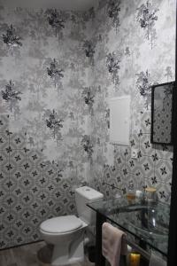 a bathroom with a toilet and a sink and wallpaper at Gîte La Tchoupetta,proche Narbonne jaccuzi, jardin, canalplus, netflix in Peyriac-de-Mer +20 photos