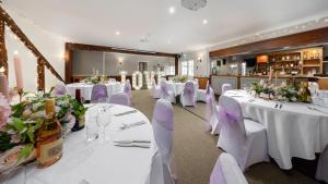 a banquet hall with white tables and chairs and flowers at The Mortimer Arms in Romsey