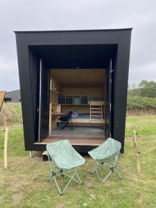 a black box with two chairs in a field at Cyclodges – Marguerite et Ferdinand in Hotton +3 photos