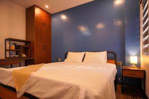 a bedroom with a large bed with a blue wall at Hotel Golden Joy Stay in Hai Phong