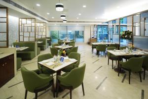 a dining room with tables and green chairs at Muse Sarovar Portico Nehru Place in New Delhi