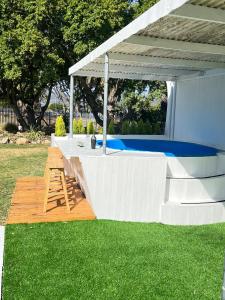 a white pergola with a ladder on a lawn at The Ocean Side Cottage in Cape Town