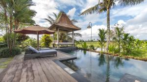 a pool with a gazebo next to a resort at The Joglo at Umah Sunset in Ubud