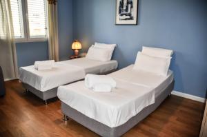 two beds in a room with blue walls at Ilia's Coastal Apartement in Vlorë