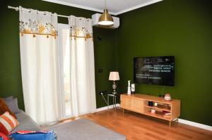 a living room with green walls and a flat screen tv at Ilia's Coastal Apartement in Vlorë