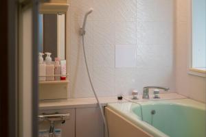 a bathroom with a bath tub and a sink at Guest House hopin in Nagano +13 photos
