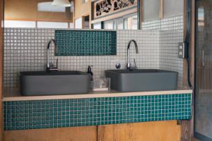 two sinks in a bathroom with green and white tiles at Guest House hopin in Nagano