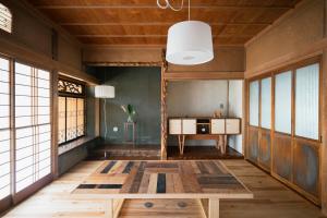 a living room with a wooden table and windows at Guest House hopin in Nagano