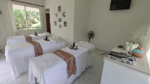 a white room with three white beds and a window at Hotel Campestre Mastranto in Villavicencio