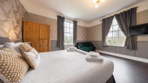 a bedroom with a large white bed and two windows at The Mortimer Arms in Romsey