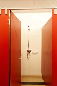 baño con cabina de ducha y puertas rojas en Albergue Monasterio de La Magdalena, en Sarria