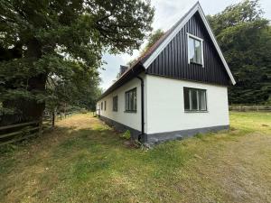 a white house with a black roof at Fiskarhuset seaside cottage 2-6 pax in Sjöbo +16 photos