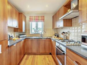 a kitchen with wooden cabinets and stainless steel appliances at 3 Bed in Chathill oc-cn001 in Beadnell +8 photos