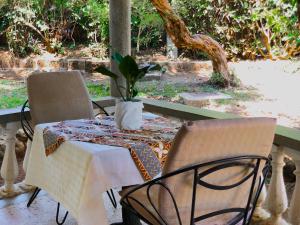 a table and chairs with a potted plant on it at Siesta Riverside Cottages Moshi in Shiri +20 photos