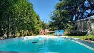 a swimming pool with two blue chairs in a yard at Refugios de Rio Ilo in Concepción del Uruguay