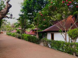 a building with a red roof next to a brick road at Siesta Riverside Cottages Moshi in Shiri