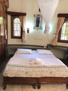 a large bed in a bedroom with two windows at Siesta Riverside Cottages Moshi in Shiri