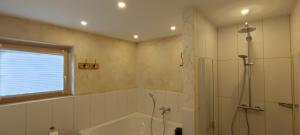 a bathroom with a tub and a shower and a window at Chalet Edelweiß in Achenkirch