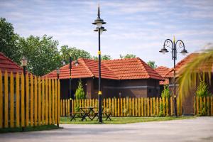 a fence with a bench and a building with red roofs at Shwetik Resort in Khamshet