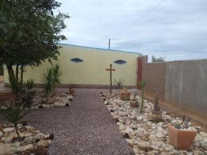 a garden with rocks and plants in front of a building at Camping Lamadrague in Opuwo +7 photos