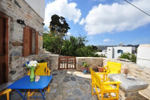 a patio with yellow chairs and a blue table at Pension Sofia Amorgos in Katapola