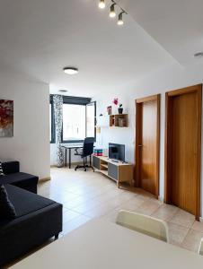 a living room with a black couch and a desk at cozy flat in Puerto del Rosario