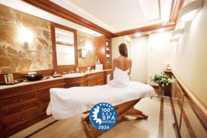 a woman sitting on a bed in a bathroom at Hotel Haffner Resort & Spa - Destigo Hotels in Sopot