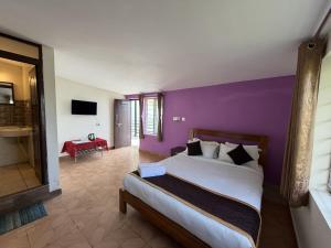 a bedroom with a bed and a purple wall at kollanoor guest house in Madikeri +81 photos