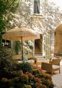 a patio with chairs and an umbrella in front of a building at L'Abbaye Hôtel in La Colle-sur-Loup