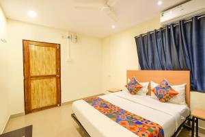 a bedroom with a bed with blue curtains and a door at FabHotel Vedhanshi in Hyderabad