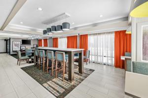 a dining room with orange curtains and a table and chairs at Hampton Inn Bloomington West in Bloomington