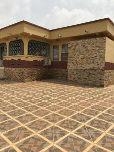 a building with a stone floor in front of it at Macdel Guesthouse And Condos in Kumasi