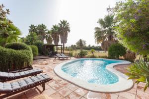 a swimming pool in a yard with chairs and trees at Villa con Vistas in Sanlúcar de Barrameda