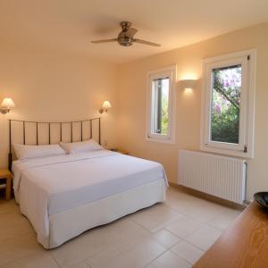 a bedroom with a white bed and two windows at Alpha Luxury Villa - Private Pool & VIP Services in Platanias