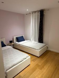 two beds sitting in a room with wooden floors at Appartement duplex T3 avec box - Paris - La Défense - Airport CDG - Parc des expositions - Stade de France - Disney - Astérix - Val D Europe in Villepinte