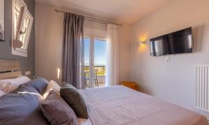 a bedroom with a bed and a tv and a window at Alkis Dream Villa with Jacuzzi in Kos
