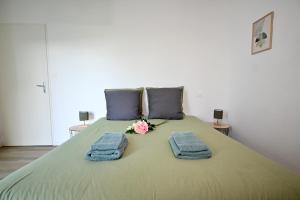 a bed with two towels and a bouquet of flowers on it at Maison moderne avec spa et jardin sans vis-à-vis, idéal professionnels et familles - L'ÉCRIN BRETON in Vannes